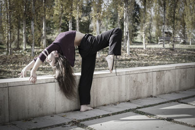 Side view of woman stretching at park during autumn