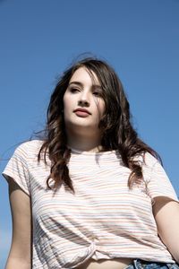 Portrait of teenage girl against blue sky