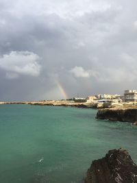 Scenic view of sea against rainbow in sky