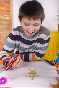 Boy with red marker pen painting a tiger.