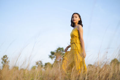 Portrait of woman standing on field against sky