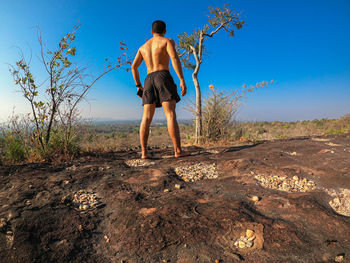 Full length rear view of shirtless man standing on ground