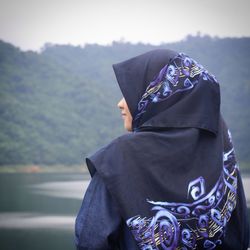 Rear view of girl in headscarf looking at lake against sky
