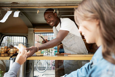 Mid adult salesman handing bread to customer at food truck