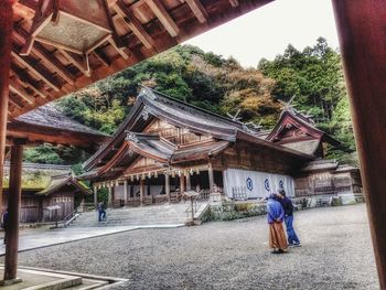 Rear view of man outside temple against building