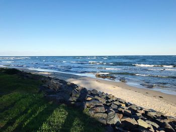 Scenic view of beach against clear blue sky