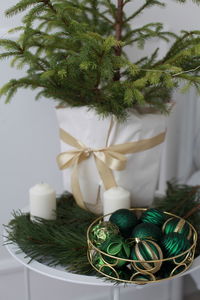 Close-up of christmas tree wrapped in paper on table among green balls and candles 