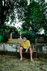 Portrait of young man sitting against plants