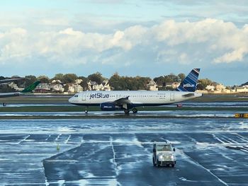 Airplane on airport runway against sky