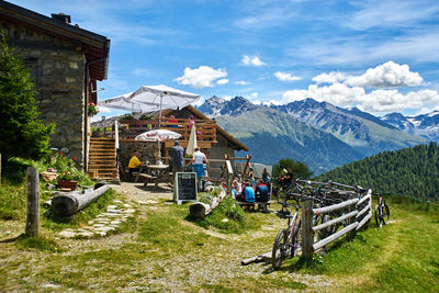 People on walkway amidst buildings and mountains against sky