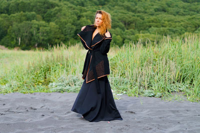 Mid adult woman wearing black dress at beach