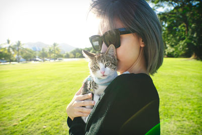 Portrait of woman with cat on grass