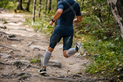 Male athlete running in forest in compression calf sleeve
