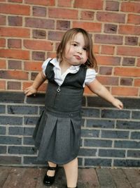 Full length of girl standing against brick wall