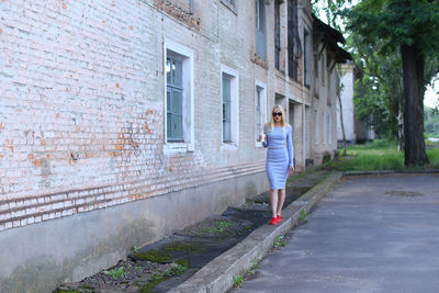 Woman standing by wall in city