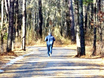 Rear view of man walking on road in forest