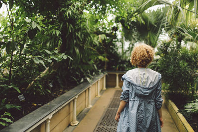 Rear view of young woman standing on footpath