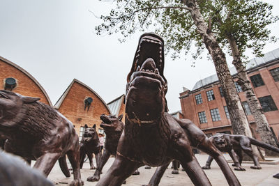 Low angle view of statue by building against sky