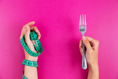 Cropped hand of woman holding heart shape against yellow background