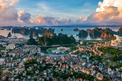 High angle view of buildings and sea against sky at sunset