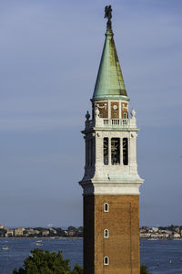 Clock tower by sea against sky in city