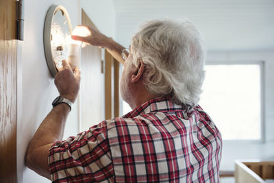 Senior man changing light bulb in sconce at home