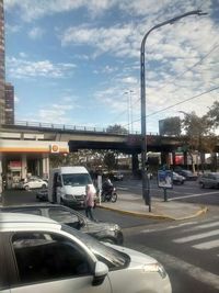 Cars on road against cloudy sky