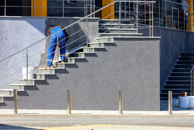 Worker in blue overalls puts decorative facade plaster on the wall of the building.