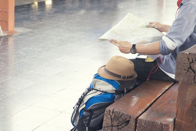 Midsection of man reading map while sitting on wooden bench