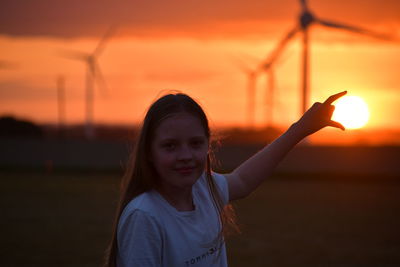 Portrait of smiling girl on land against sky during sunset