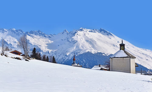 Chapel in a rural village between field and mountain covered with snow in winte