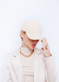 Portrait of young woman wearing hat against white background