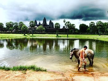 Men standing by lake against sky