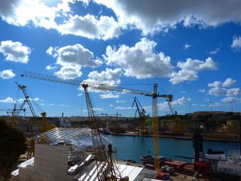 Cranes at harbor against sky