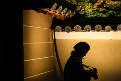 Rear view of silhouette boy standing in illuminated building