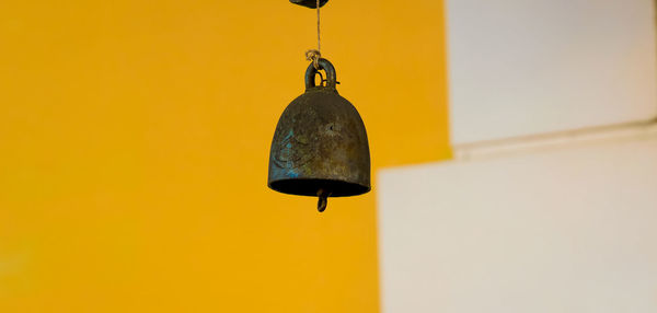 Low angle view of pendant light hanging on yellow wall