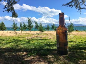 Abandoned bottle on field against sky