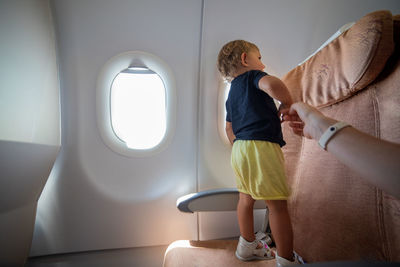 Full length of boy standing by airplane window