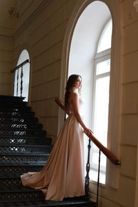 Side view of woman standing against staircase