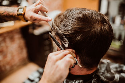 Cropped hands of barber grooming customer in salon