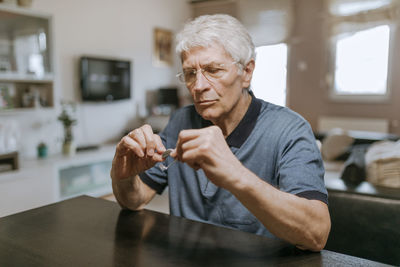 Portrait of senior man using mobile phone while sitting at home