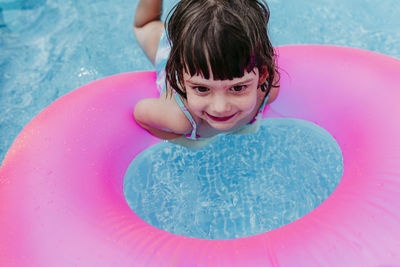 High angle view of smiling girl with inflatable ring in swimming pool