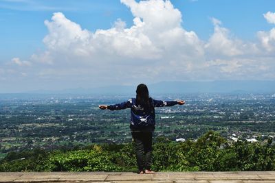 Rear view of woman standing by sea against sky