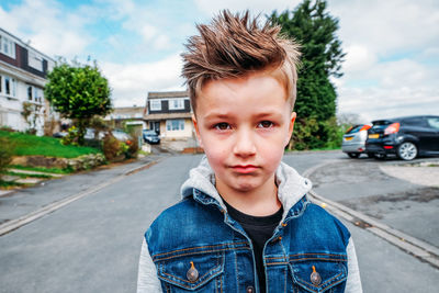 Portrait of boy standing on road against sky