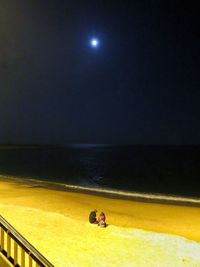 People in sea against sky at night