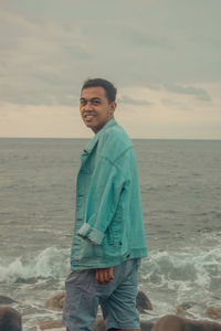 Mid adult man standing at beach against sky