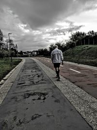 Rear view of man walking on road