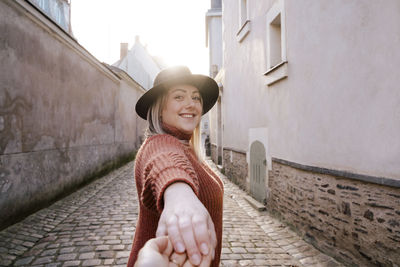 Portrait of woman holding hand in alley