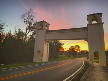 Road by bridge against sky during sunset