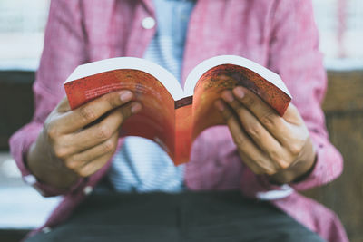 Midsection of man holding book